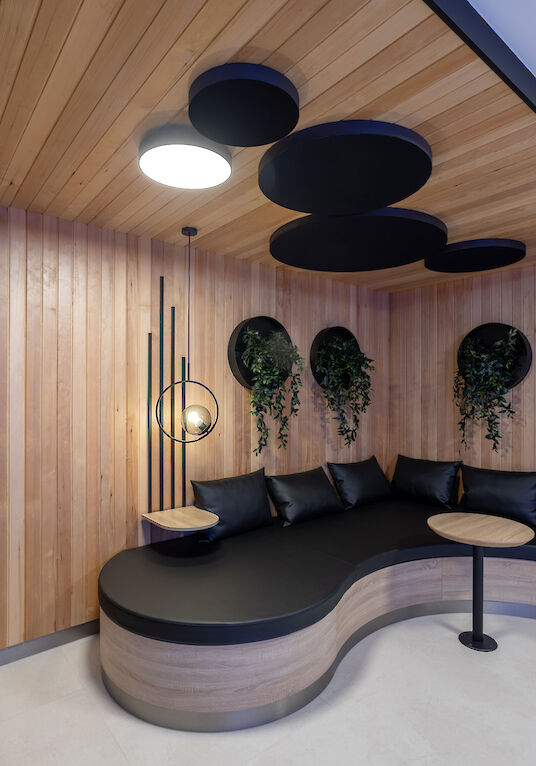 Sauna area with organic bench, wooden panelling, round Basic surface-mounted luminaire and hanging plants.