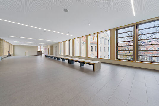 Spacious hallway with bench, floor-to-ceiling windows and linear Matric recessed lighting.