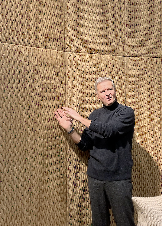 Francis Vercaemst se coloca delante de un muro acústico estructurado y explica la textura tridimensional del material.