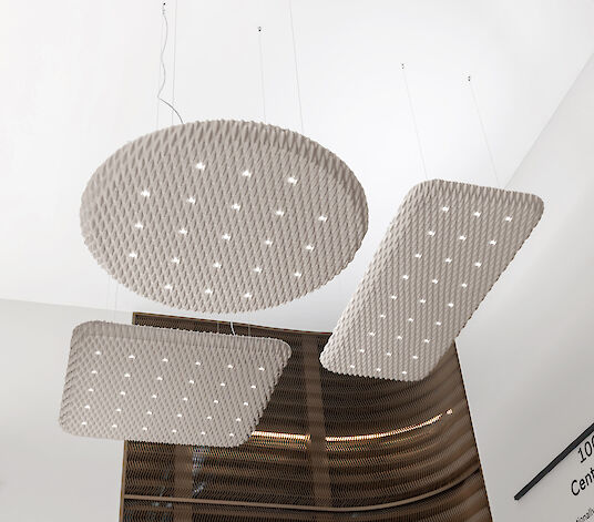 Tres luminarias acústicas suspendidas Serenity de gran formato en una sala de exposiciones
