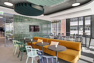 Modern canteen design with colourful chairs, mustard yellow sofa and round basic pendant luminaires.