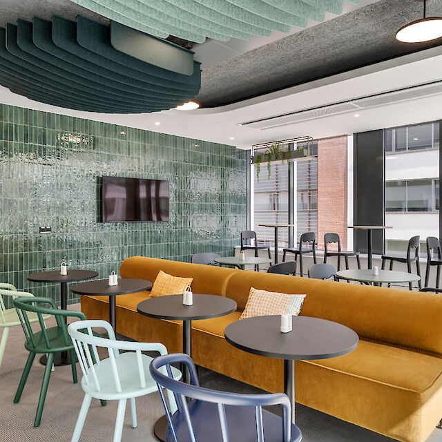 Modern canteen design with colourful chairs, mustard yellow sofa and round basic pendant luminaires.